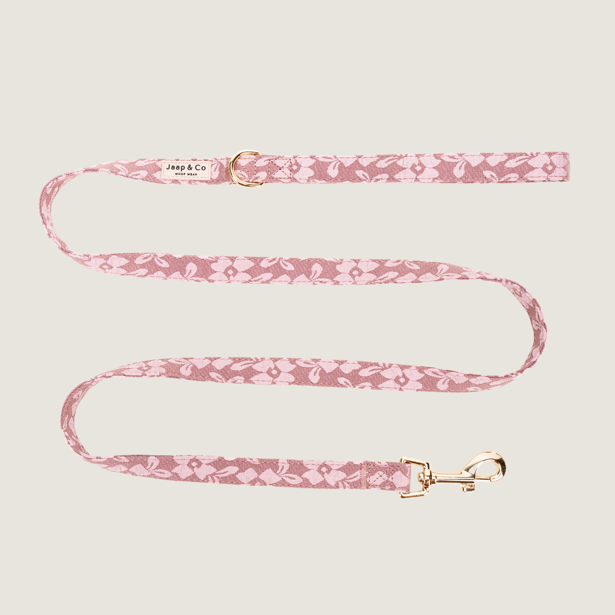 Oud roze hondenriem met lichtroze bloemenprint en gouden details, bevat een D-ring om poepzakjeshouder aan vast te klippen. Er zijn bijpassende producten van de Rosé Dusk van Jaap & Co