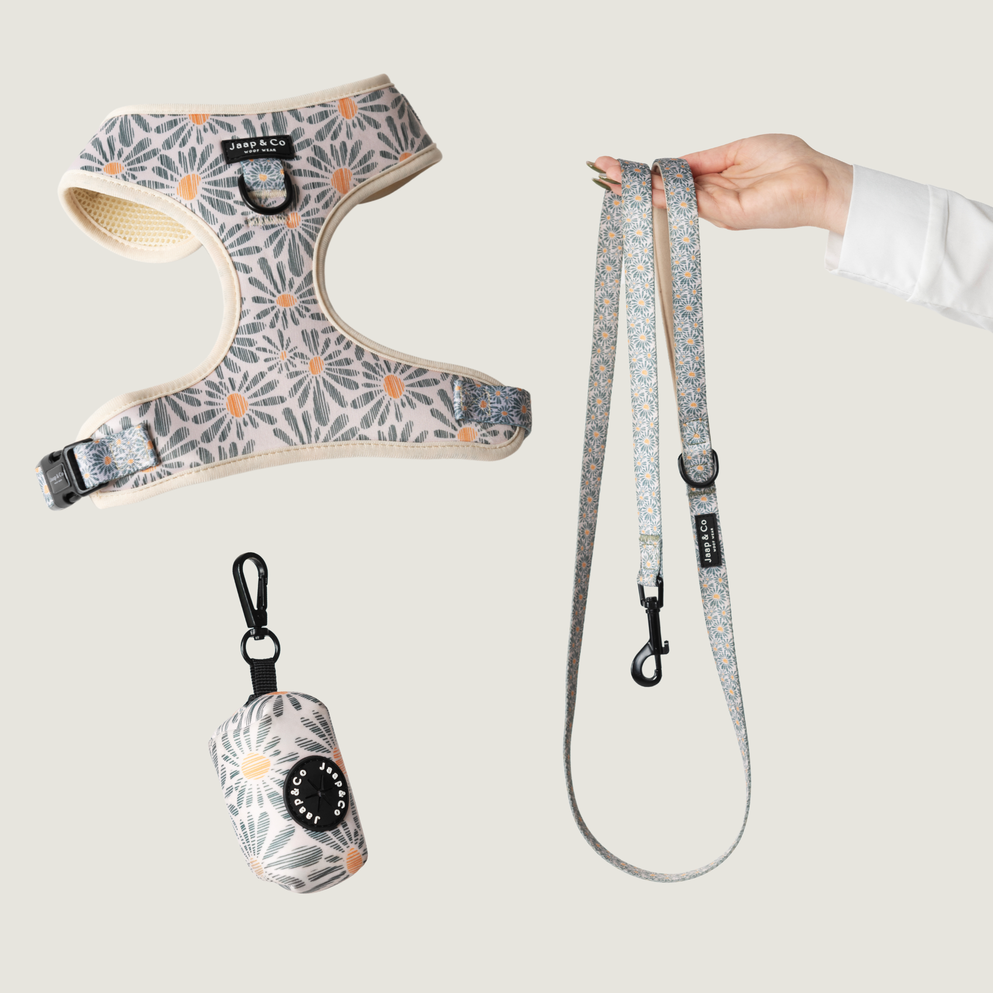 Set met hondentuigje, riem en poepzakjeshouder van de Floral Memories van de Jaap & Co collecties. Is een licht beige achtergrond met licht grijs blauwige bloemen en oranje accent van de bloem, een mooie neutrale bloemenprint.