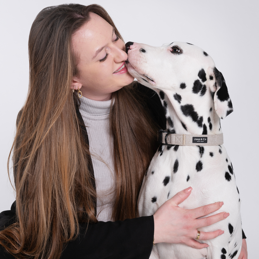 Model met dalmatiër die een Jaap &amp; Co Classic Beige hondenhalsband draagt – close-up moment van verbinding