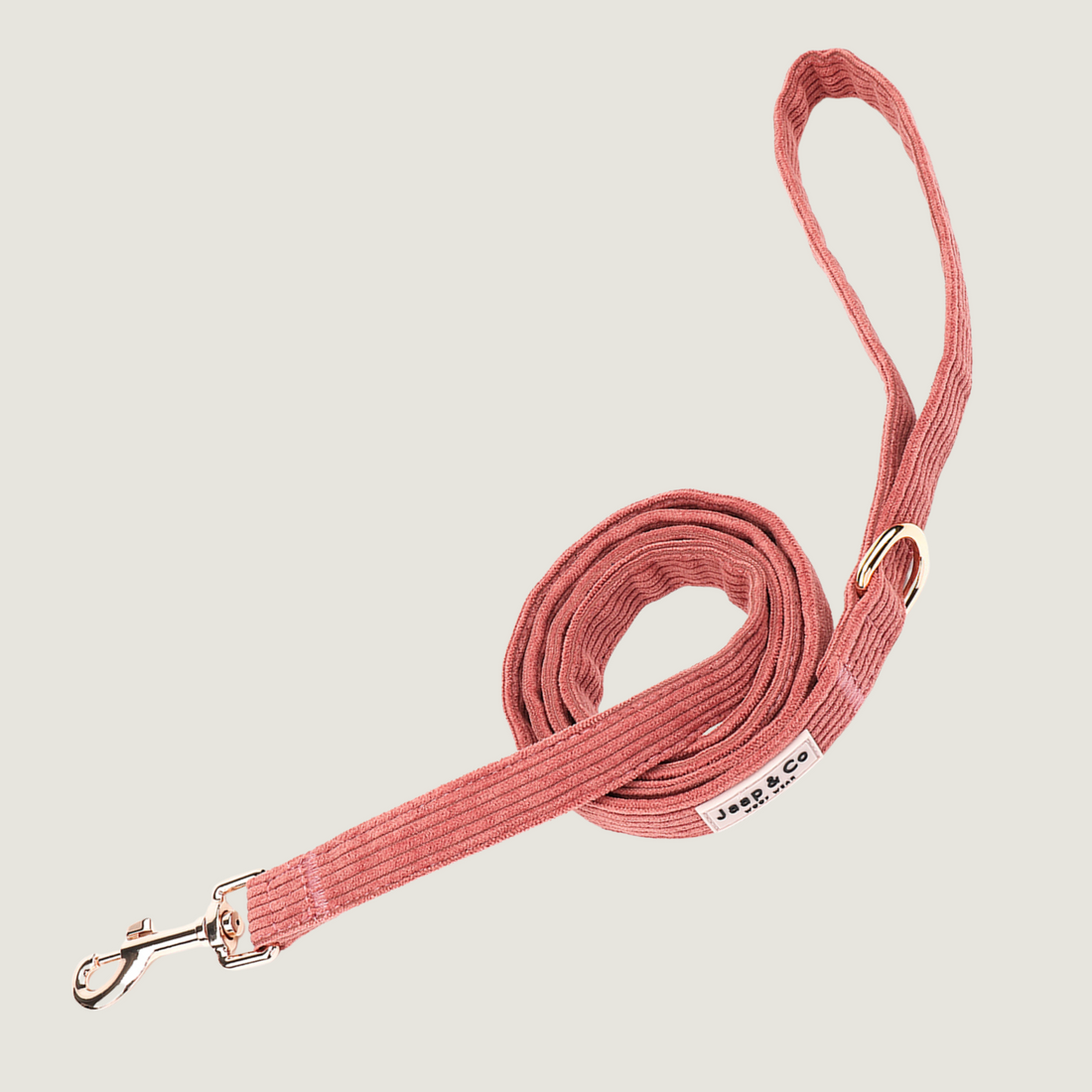 Koraalkleurige corduroy hondenriem uit de Jaap & Co Golden Trails collectie, met goudkleurige metalen details en extra ring voor poepzakjeshouder, geïnspireerd op nazomerse wandelingen.