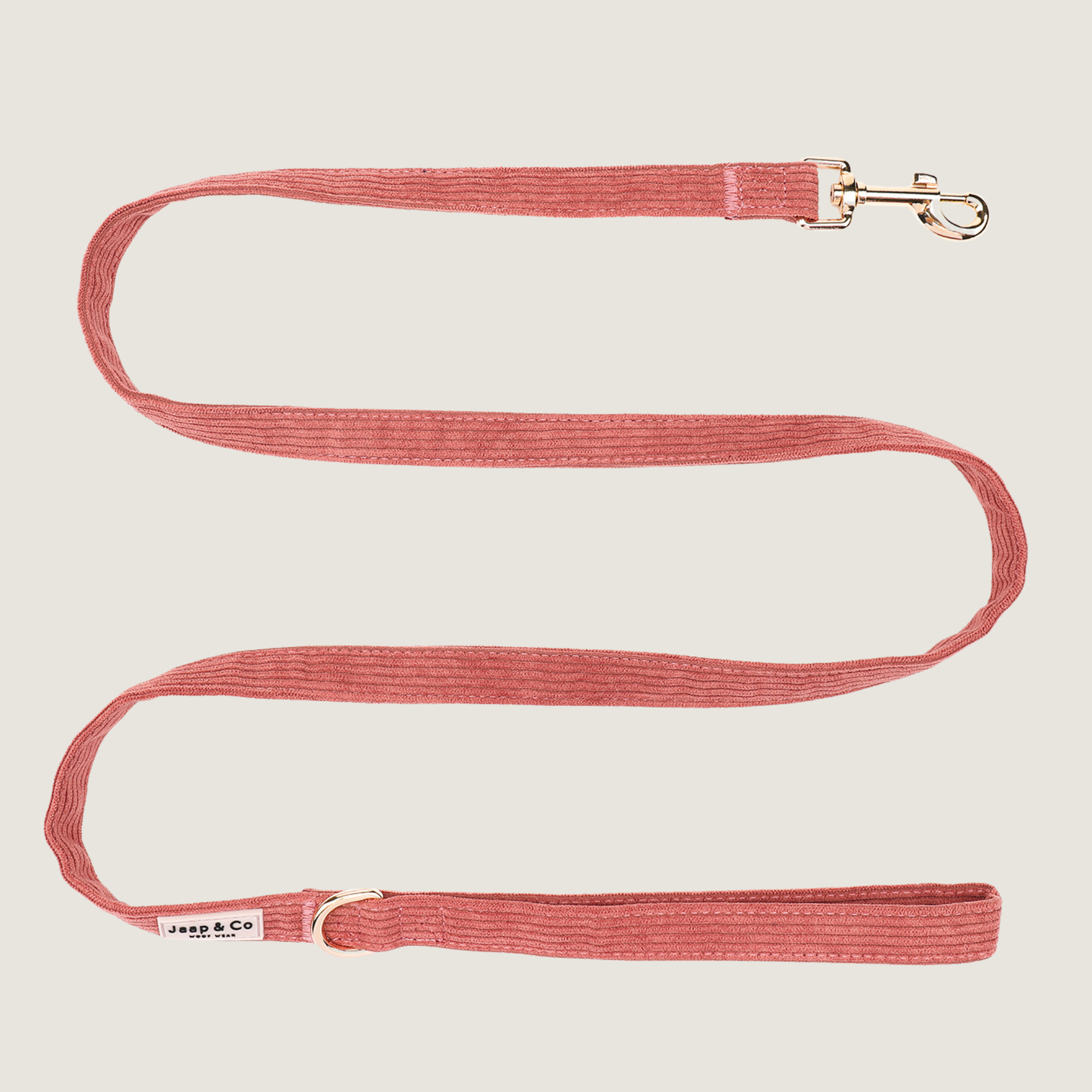Koraalkleurige corduroy hondenriem uit de Jaap &amp; Co Golden Trails collectie, met goudkleurige metalen details en extra ring voor poepzakjeshouder, geïnspireerd op nazomerse wandelingen.