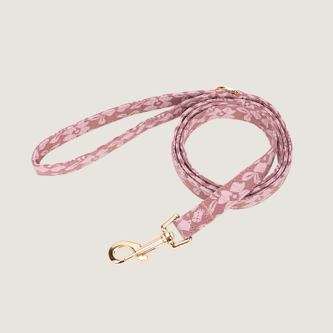 Oud roze hondenriem met lichtroze bloemenprint en gouden details, bevat een D-ring om poepzakjeshouder aan vast te klippen. 