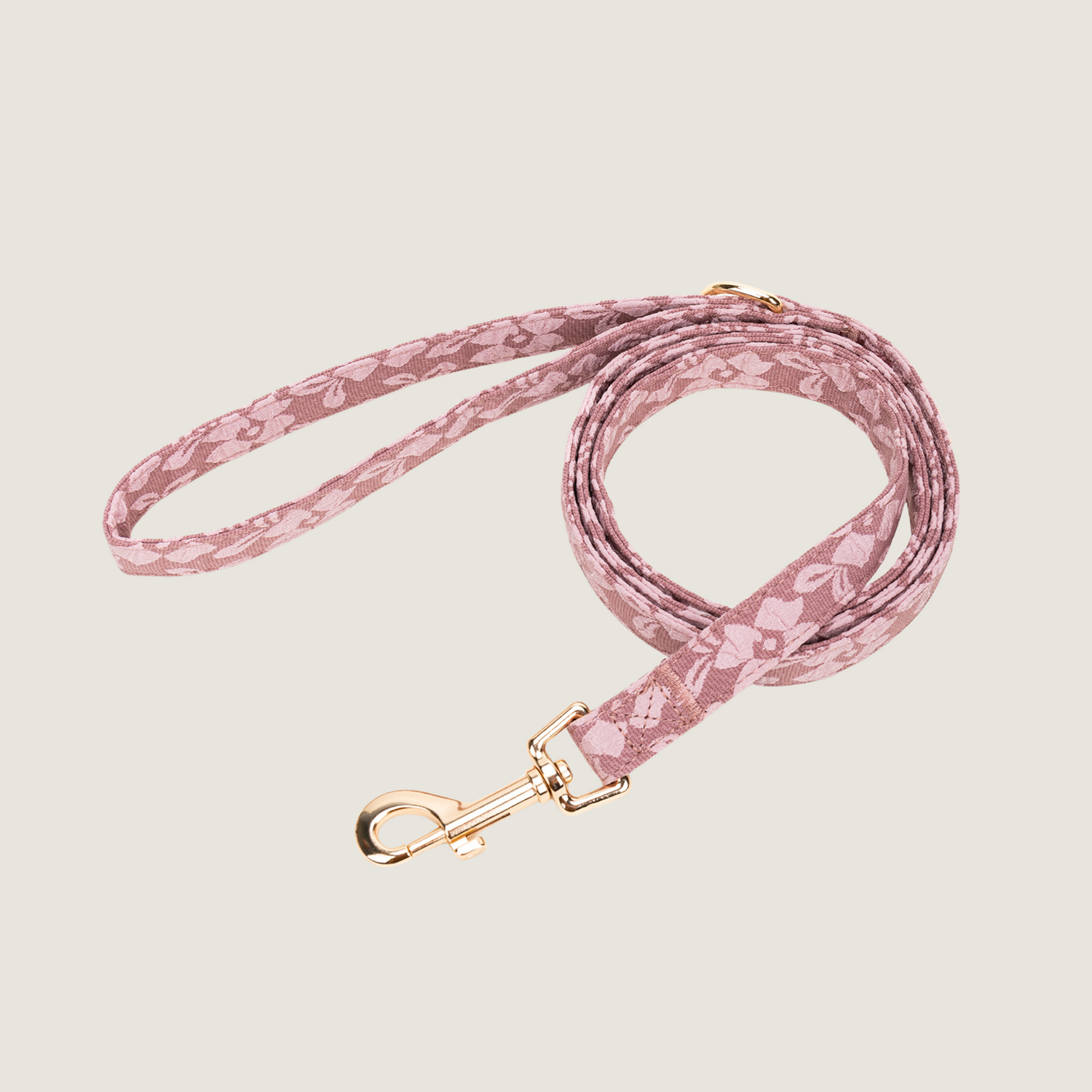 Oud roze hondenriem met lichtroze bloemenprint en gouden details, bevat een D-ring om poepzakjeshouder aan vast te klippen. 