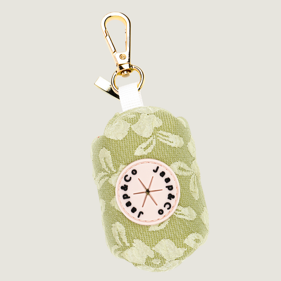 Jaap & Co Botanical Glow collectie: een lichtgroene poepzakjeshouder met lichtere geborduurde bloemenprint met gouden hardware